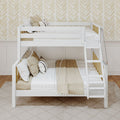 White wooden bunk bed with ladder, neutral beige pom-pom pillows and textured throw blankets against chevron wallpaper in a modern kids' bedroom