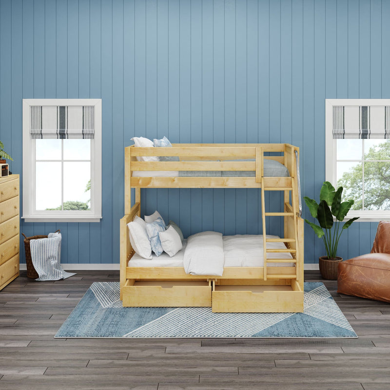 Natural wood twin-over-full bunk bed with pull-out storage in a bright kids' bedroom featuring a blue paneled wall, hardwood floor, patterned rug and large windows