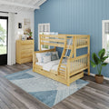 Natural wood twin-over-full bunk bed with ladder, safety rails and trundle drawer in a coastal-style kids' bedroom with blue shiplap wall, wooden dresser, gray-blue geometric area rug, potted plant and hardwood floors