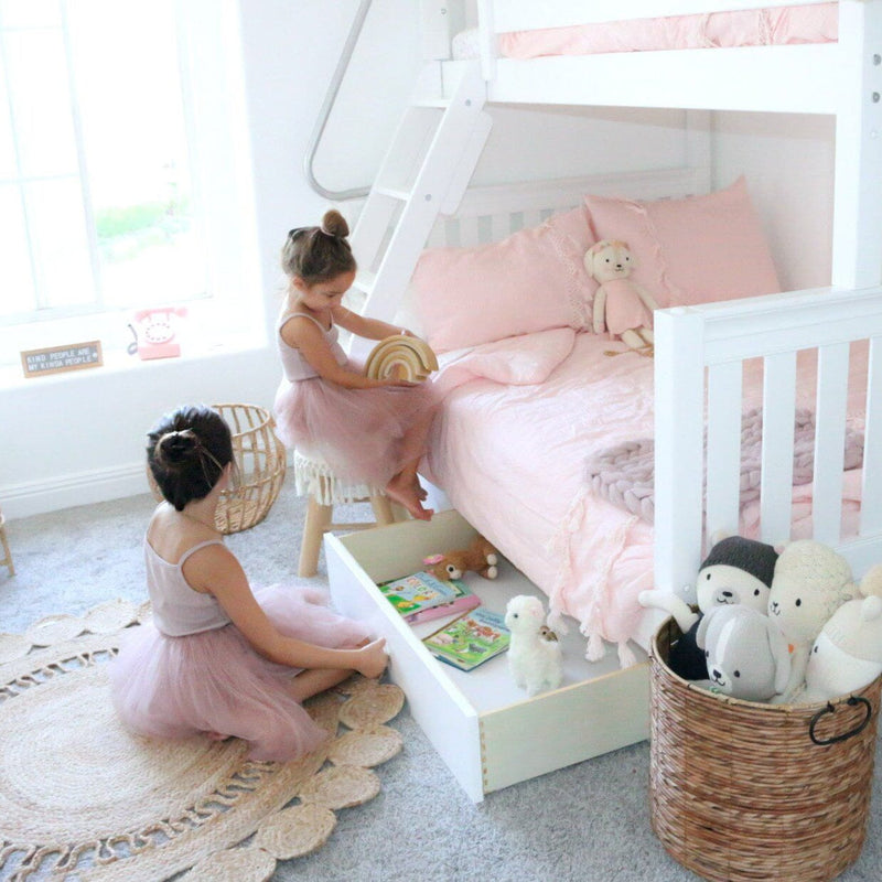 Two young girls in tulle dresses playing by a white bunk bed with pink bedding and under-bed toy storage in a pastel kids' bedroom