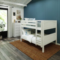 White bunk bed in coastal kids' bedroom with navy blue paneled accent wall, white dresser, jute rug and hardwood floor