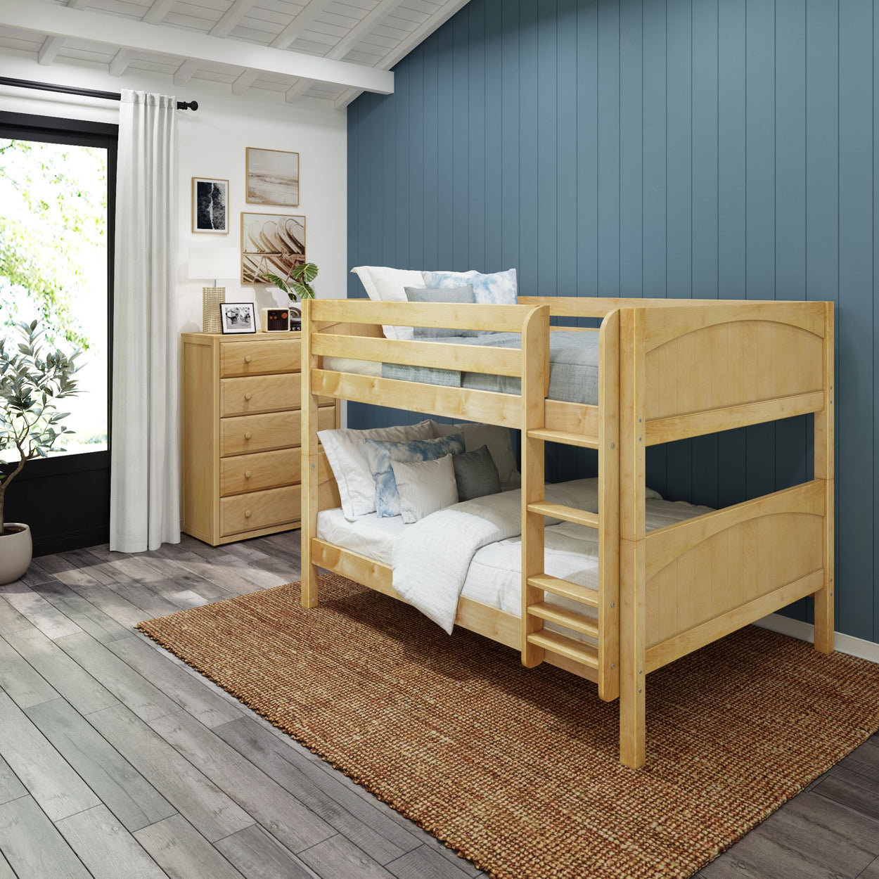 Wooden bunk bed with natural finish in cozy bedroom setting, featuring blue accent wall, wooden dresser, and decorative wall art.