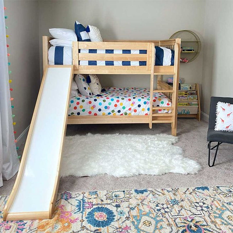 Natural wood kids bunk bed with slide and ladder in a bright children's bedroom, polka-dot bedding, lower play area, round wall shelf and white shag rug
