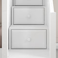 Close-up of white built-in staircase drawers with recessed panel fronts and round knobs, modern under-stair storage solution
