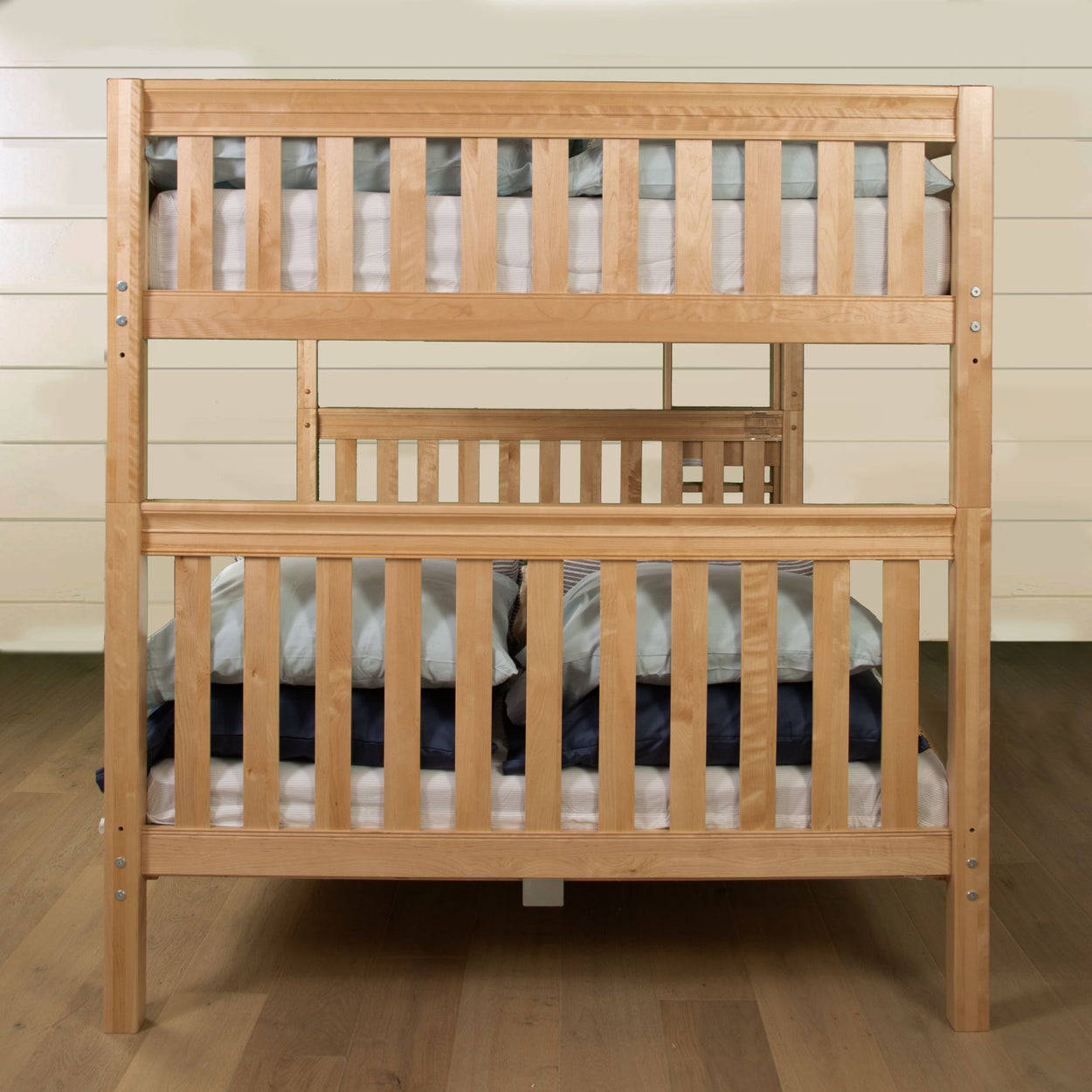 Wooden bunk bed with mattresses and pillows in a modern bedroom setting.