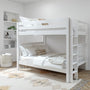 Modern white wooden bunk bed with ladder and guardrail in a neutral kids' bedroom, layered white and beige bedding, built-in shelving with decor, woven storage basket and patterned rug