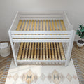 White convertible baby crib frame with natural wood slats, boho rug and potted plant in modern nursery