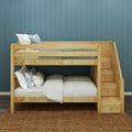 Wooden bunk bed with built-in stairs and storage drawers in kids bedroom, natural wood finish with white and blue bedding against a blue paneled wall on a woven jute rug