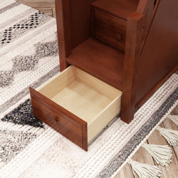 Open wooden drawer in a stair-step cabinet on patterned floor rug.