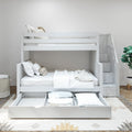 White wooden bunk bed with pull-out trundle and built-in staircase storage in a modern neutral kids' bedroom with white linens and potted plant