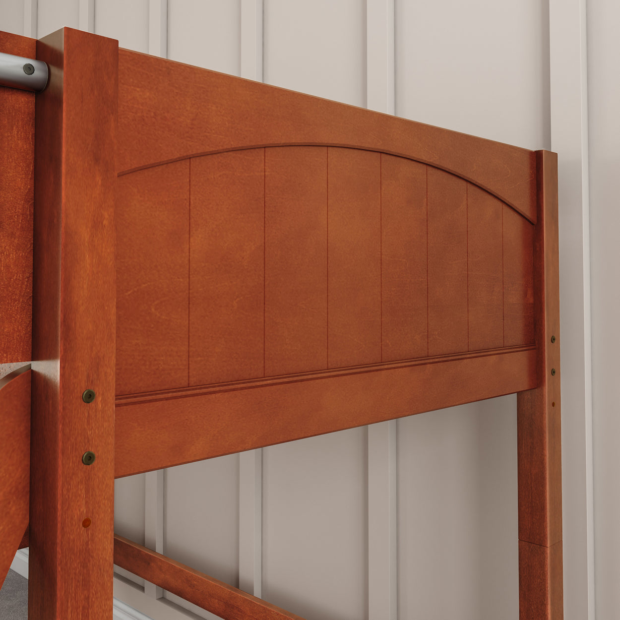 Wooden bed frame close-up with a classic headboard design against a paneled wall background.