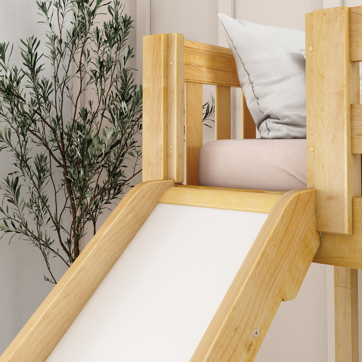 Wooden indoor play slide for toddlers with a cushioned seat and decorative plant.