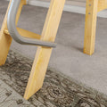 Close-up of light wooden stepladder legs with curved metal handrail on gray carpeted floor in a home interior