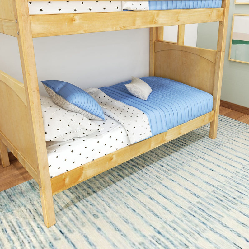 Natural wood twin bunk bed with blue quilted bedding and star-print sheets in a kids' bedroom with textured area rug