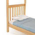 Natural wood slatted headboard and twin bed frame with white pillow and light blue quilted blanket
