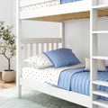 White wooden bunk bed with blue quilted bedding and star-patterned sheets in a bright kids' bedroom with ladder and potted plant