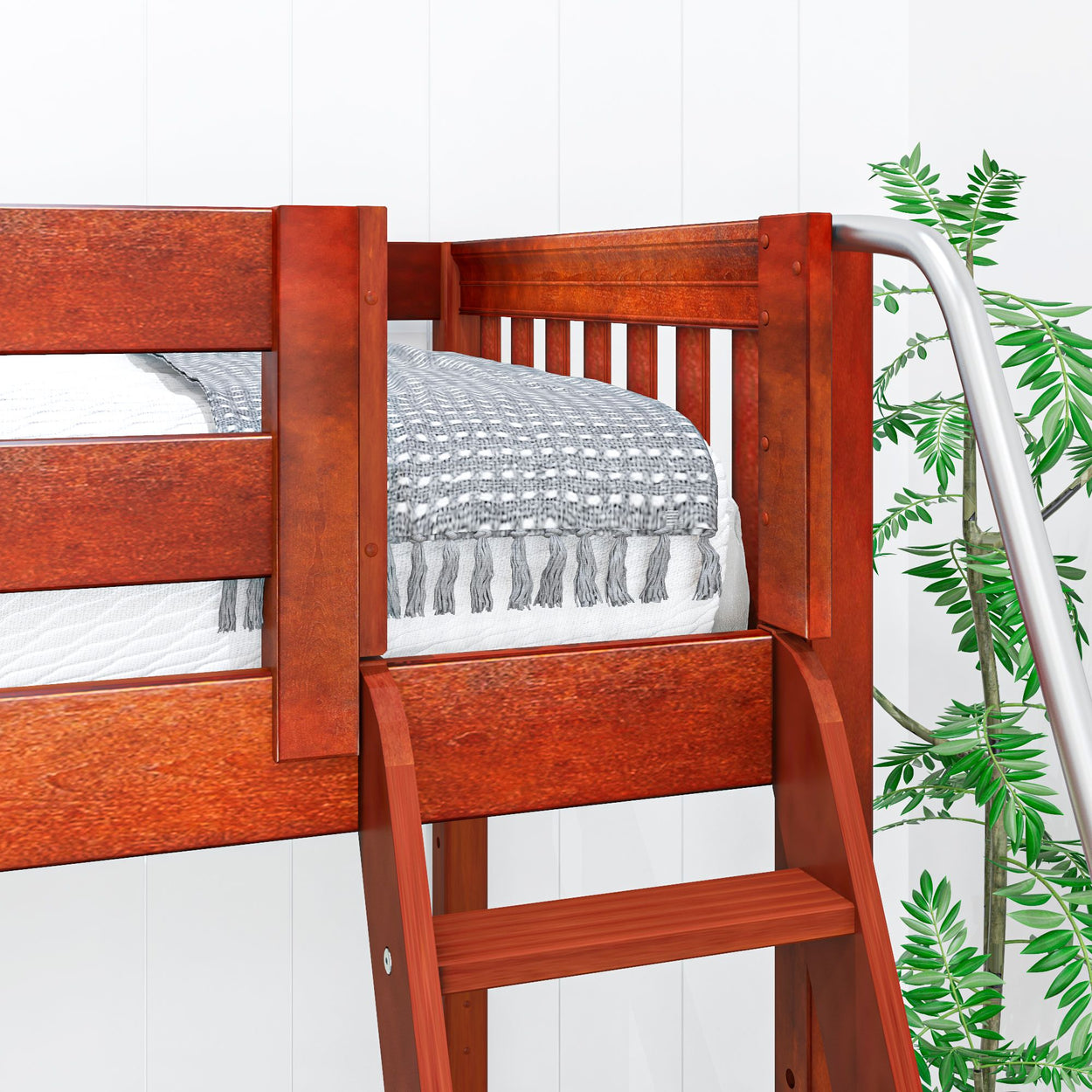 Wooden loft bed with ladder and cozy bedding next to green plant.