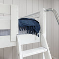 White wooden bunk bed ladder with guardrail and navy fringed throw on mattress against light shiplap wall, kids bedroom decor
