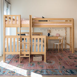 Natural wood twin bunk bed with ladder and pink bedding in a bright children's bedroom, featuring a small study desk, fairy string lights and a patterned boho rug