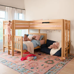 Two children in a bright kids bedroom with a wooden bunk bed, pastel pink and blue bedding, floral area rug and cozy play nook by a sunlit window