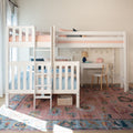 White wooden bunk bed in children's bedroom with pink and blue bedding, ladder and loft desk, string lights, wicker basket and colorful patterned area rug