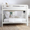 White wooden bunk bed with top loft and lower bed, white linens and decorative pillows in a bright modern kids' bedroom with hardwood herringbone floor and potted plant
