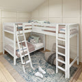 White wooden twin bunk beds with ladders and guardrails in a cozy neutral kids' room with patterned pillows, layered rugs and beige paneled walls