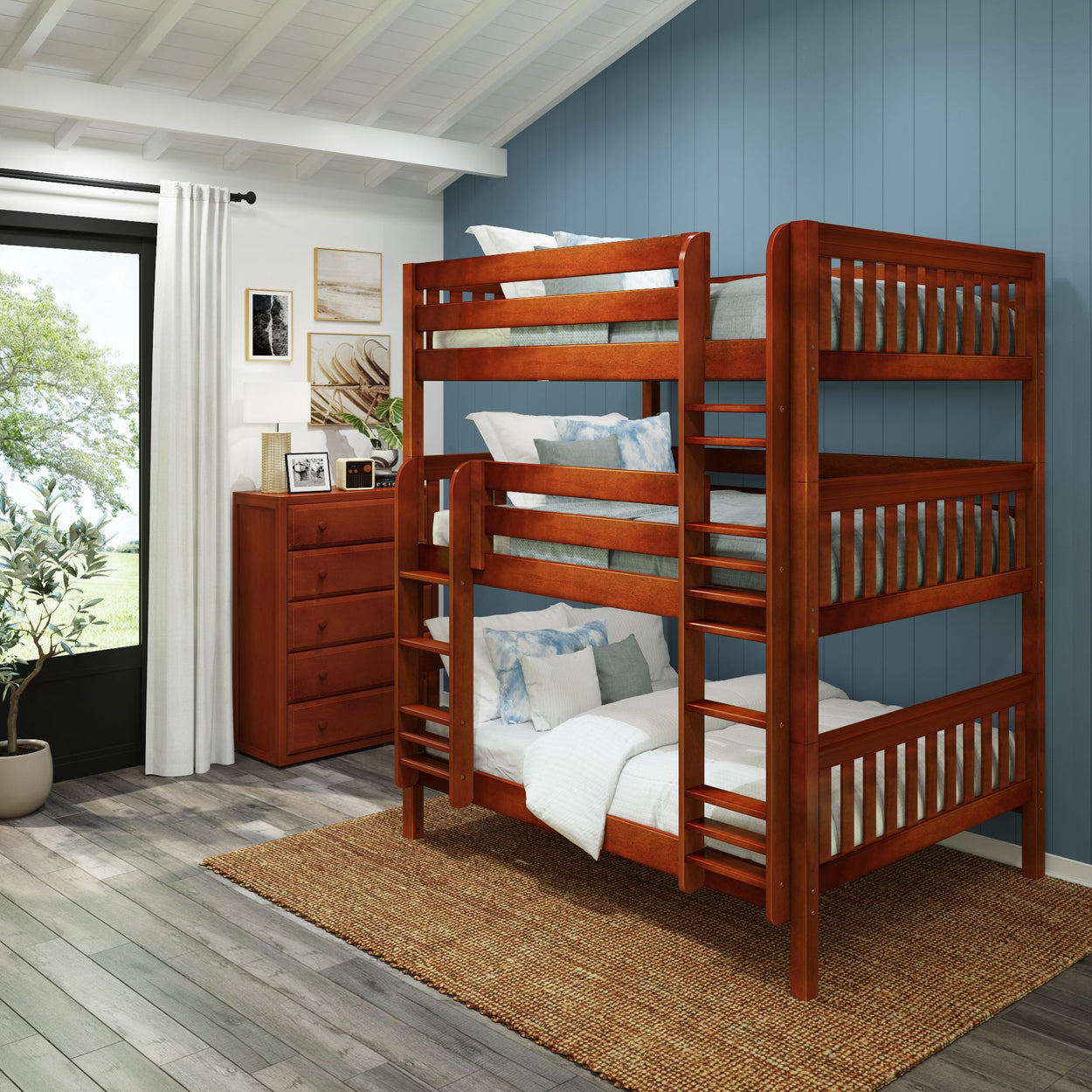 Triple bunk bed with rich wood finish in a modern, cozy bedroom featuring blue accent wall and natural lighting.