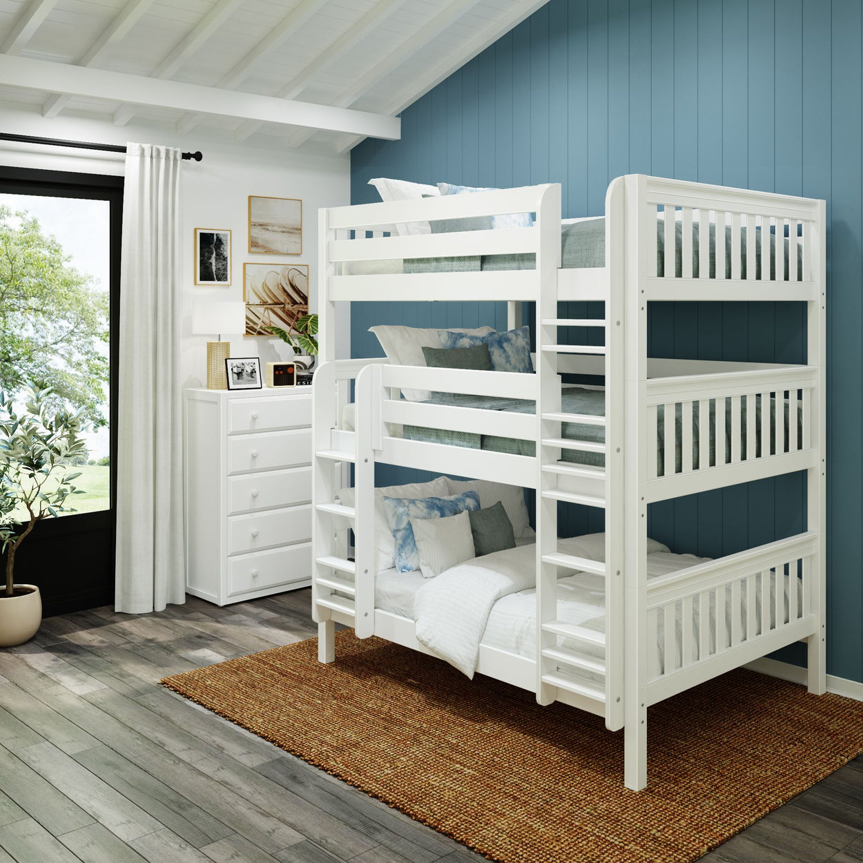 White triple bunk bed in a modern bedroom with blue accent wall and natural lighting.