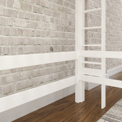 Loft bed with white frame against exposed brick wall over hardwood floor.