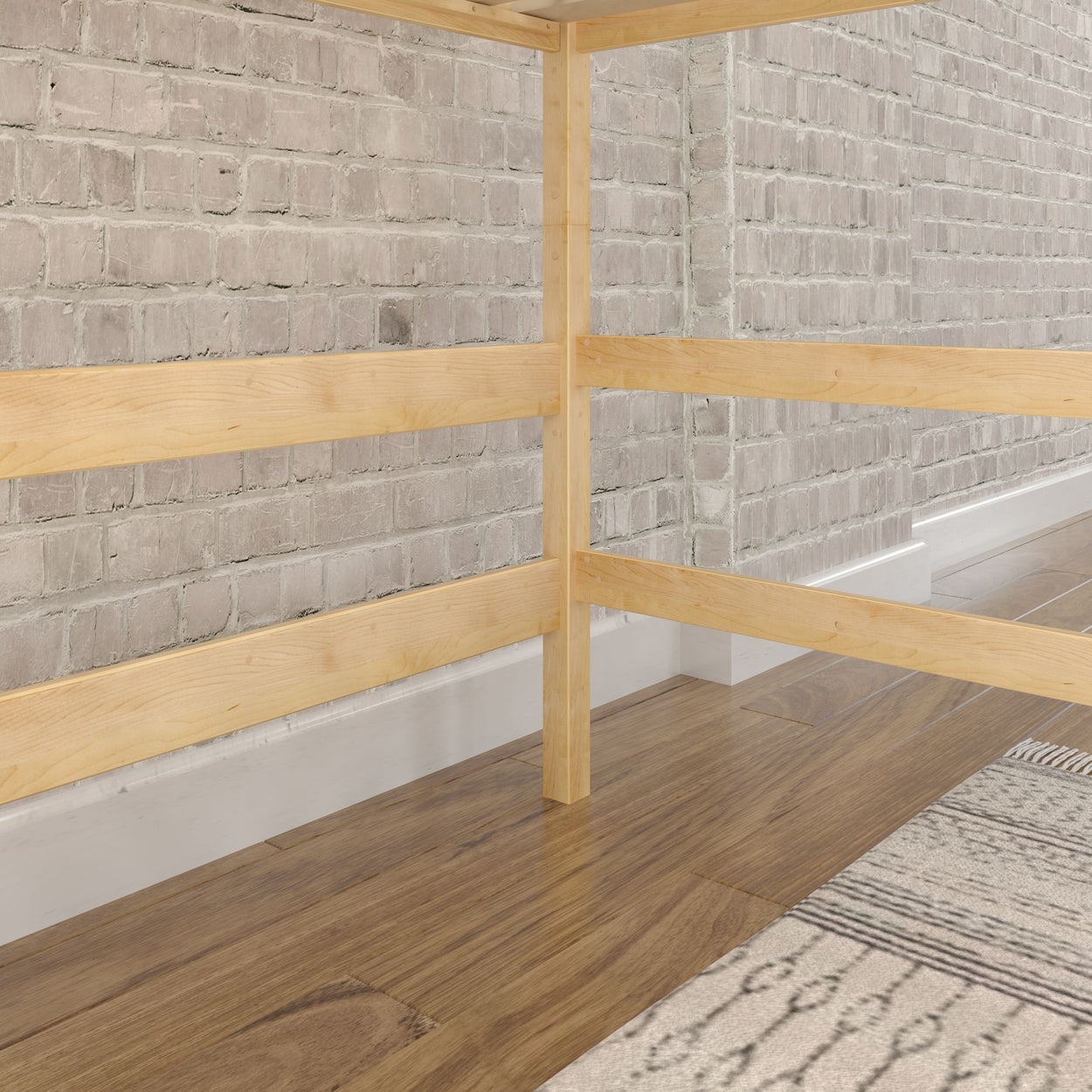Simple wooden bed frame on hardwood floor with brick wall background.