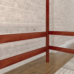 Red wooden bed frame with white brick wall backdrop and hardwood flooring in a modern bedroom.
