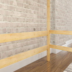 Wooden modern staircase railing with beige brick wall background and hardwood floor.