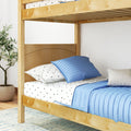 Natural wood bunk bed with blue bedding and star-print sheets in a kids' bedroom, potted plant nearby