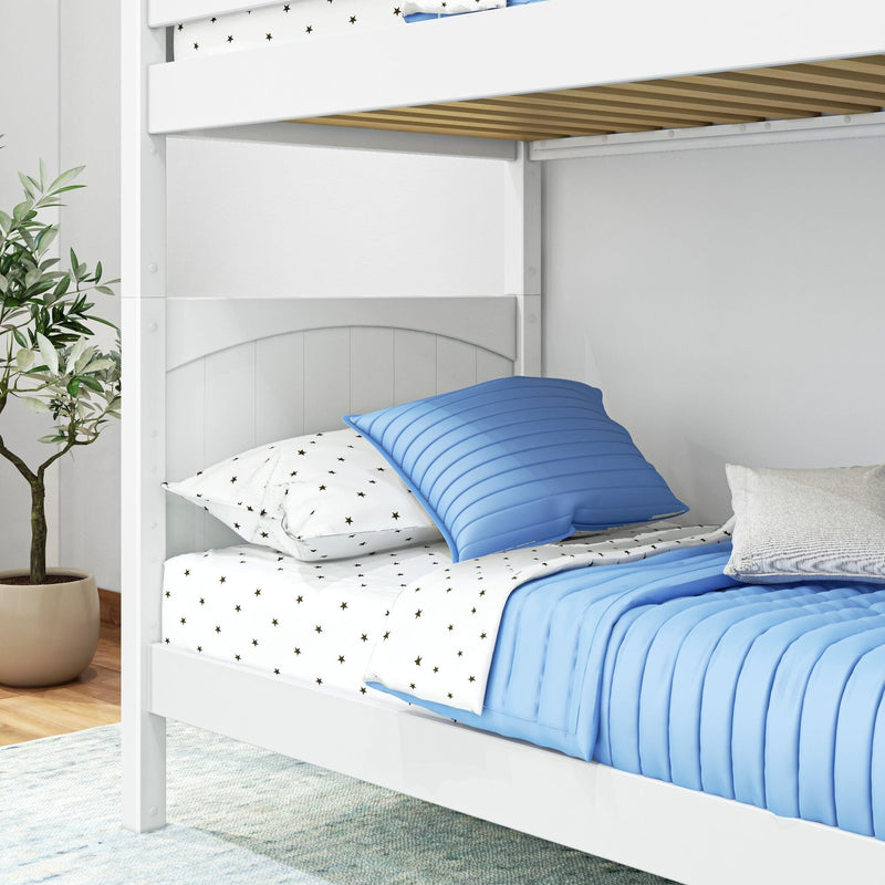 White wooden bunk bed with blue quilted bedding and star-pattern sheets in a bright children's bedroom, slatted upper frame, under-bed storage drawer and potted plant