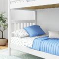 White wooden bunk bed with blue quilted pillows, star-print sheets, visible wooden slats and potted plant in a modern kids' bedroom