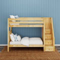 Wooden bunk bed with built-in storage stairs, white bedding and pillows against a blue paneled wall — space-saving kids' bedroom design
