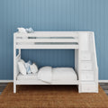 White wooden bunk bed with built-in stair storage and drawers, white bedding and blue accent pillows against a coastal blue paneled wall on a woven jute rug