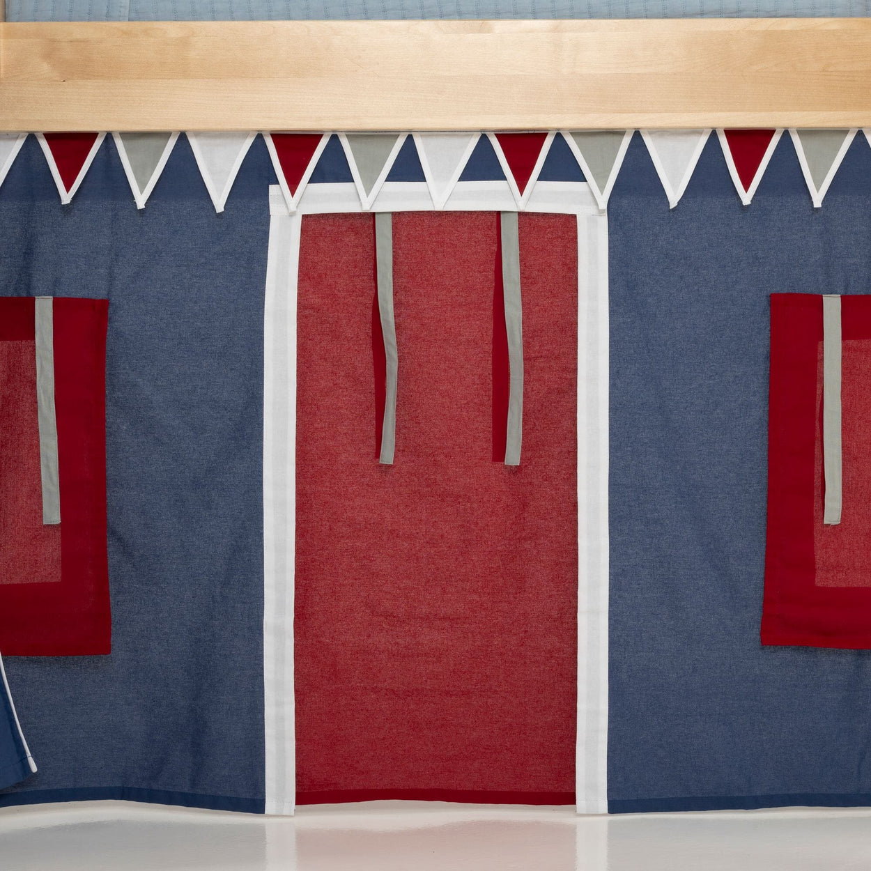 Children's indoor fabric playhouse facade with navy blue walls, red curtain door and window flaps, and white triangular pennant bunting