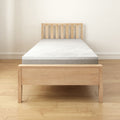 Wooden bed frame with comfortable mattress in minimalist bedroom setting.