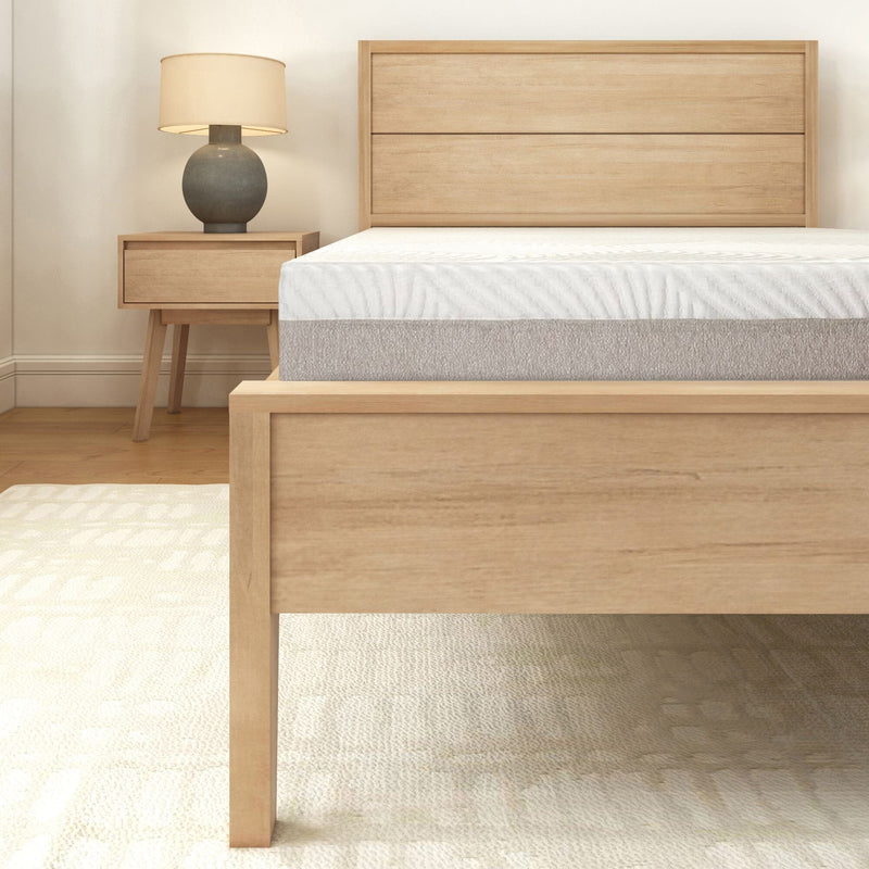 Modern wooden bed frame with a comfortable mattress and stylish bedside lamp in a cozy bedroom setting.