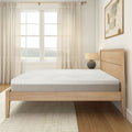 Modern minimalist bedroom with wooden bed frame and white mattress near large window.