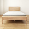 Minimalist wooden bed frame with a comfortable modern mattress in a bright room.