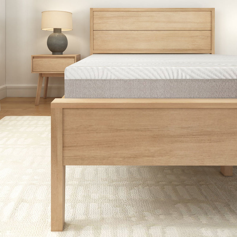 Wooden bed frame with comfortable mattress and modern bedside table in cozy bedroom setting.