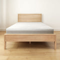 Modern wooden bed frame with comfortable mattress in minimalist bedroom setting.