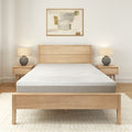 Modern minimalist bedroom with light wood furniture and abstract artwork.
