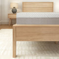 Contemporary wooden bed frame with plush mattress in a minimalist bedroom setting.