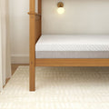 Modern wooden bunk bed frame with a comfortable mattress in a well-lit bedroom.