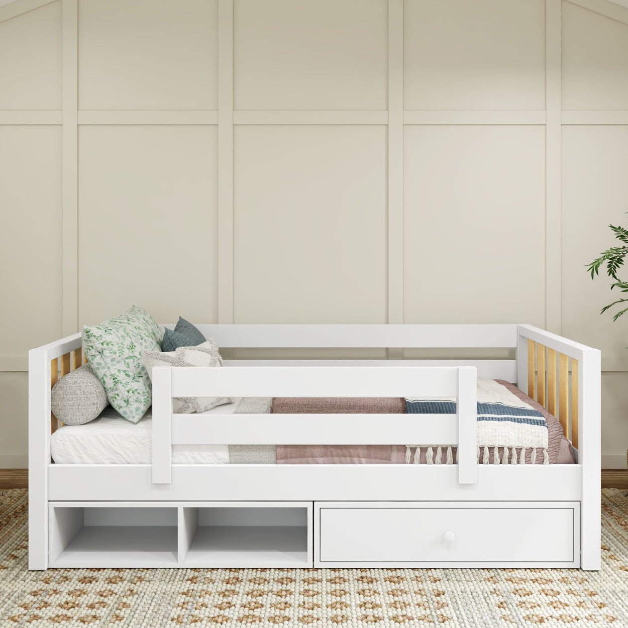 White children's daybed with storage drawers and patterned pillows in a cozy bedroom.