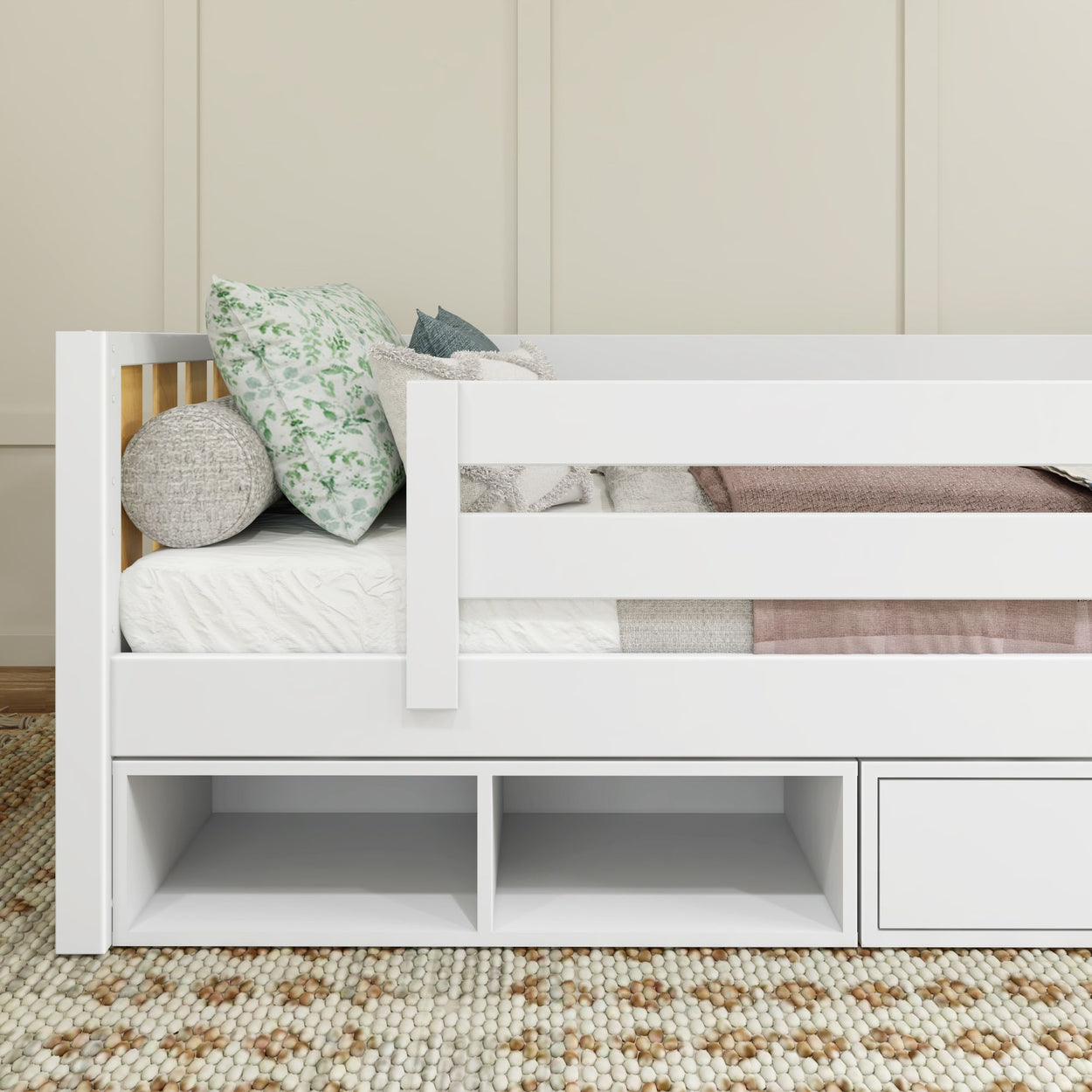 White kids' bed with built-in storage, decorative pillows, and cozy bedding on a textured rug.